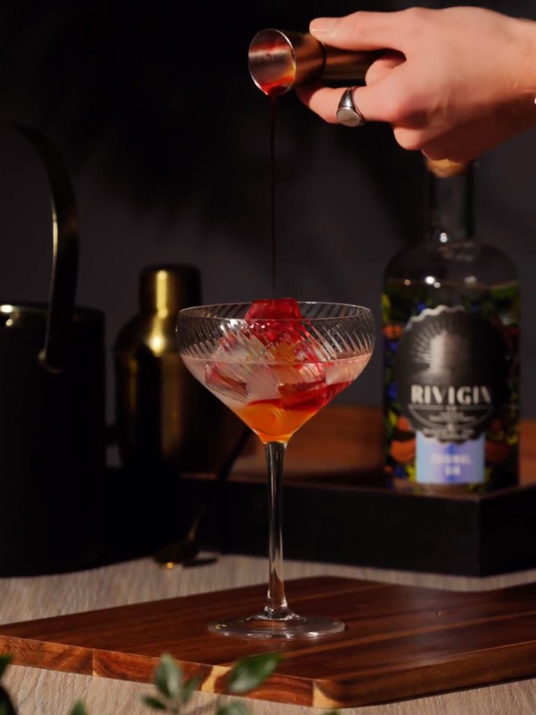 Pouring a shot of red liquid into a glass - a scene captured at a video production company.