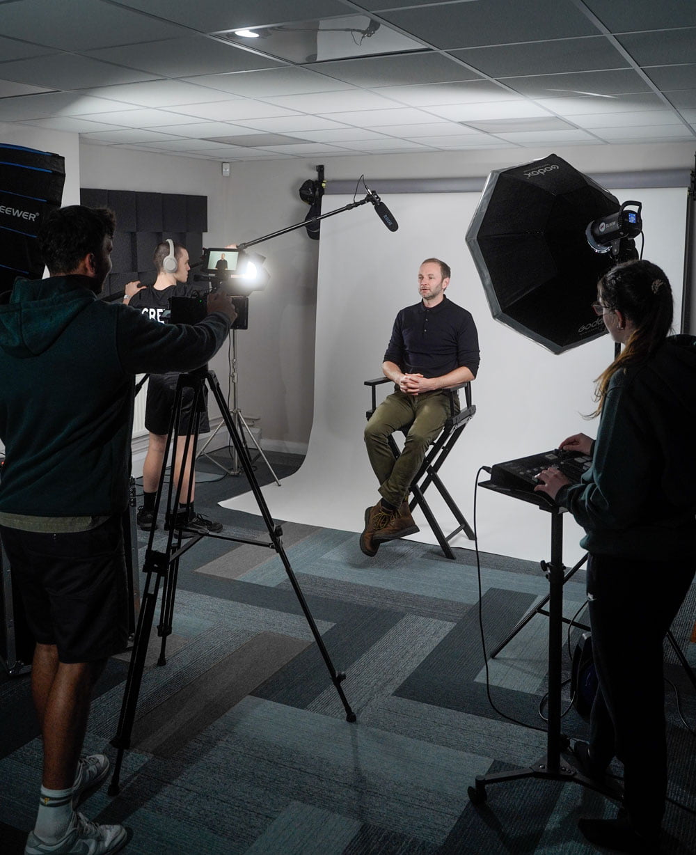 A group of people in a video production company studio with a camera and a tripod, with lighting and audio equipment, ready to capture a moment. Video Production Company in Preston