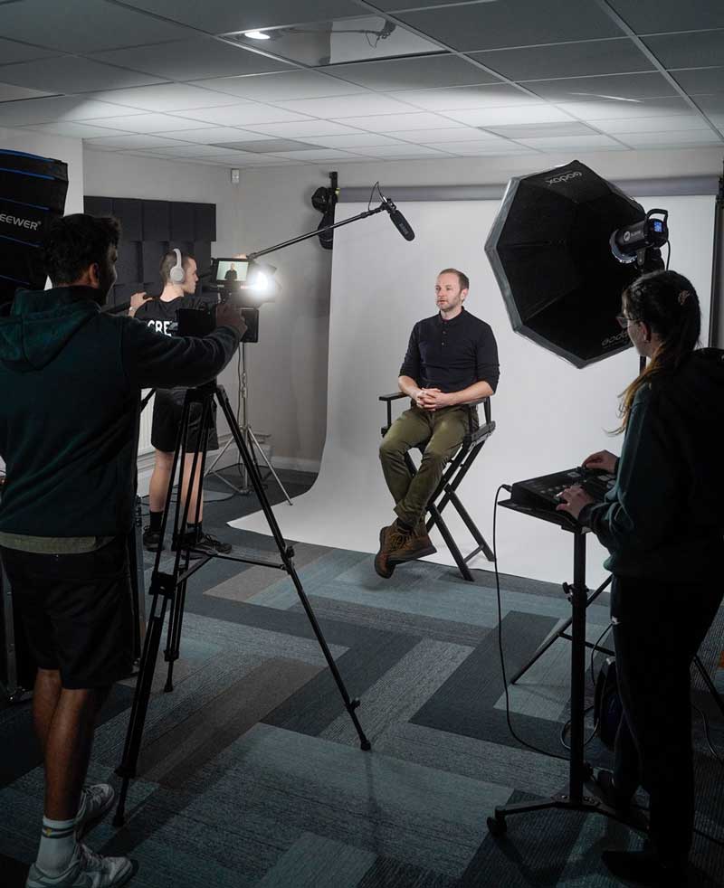 A group of people in a video production company studio with a camera and a tripod, with lighting and audio equipment, ready to capture a moment. In-house video editing. Studio Facilities
